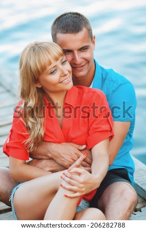 The happy young couple walking on a wooden pier on the seashore and are dressed in fashionable clothes. Having fun.