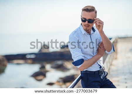 Fashion young man holding his fashionable sunglasses outdoor