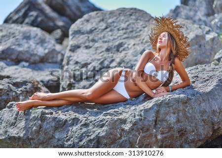 Sexy woman in a swimsuit relaxing on the beach. Tan skin