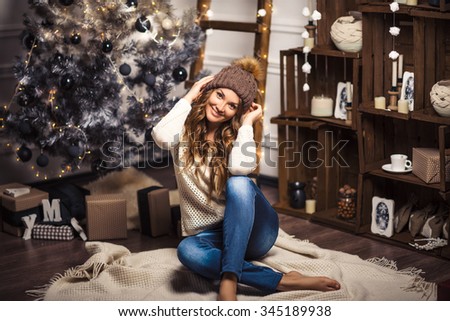 Christmas Gift. New year celebration. Beautiful holidiay decorated room with Christmas tree with presents under it. New Year and Christmas concepts. Beautiful girl sitting near New Year tree.