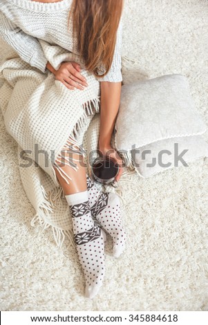 Young beautiful woman in warm knitted handmade clothes at home. Model fashion shooting. Autumn, winter season. Gaiters. Golfs. Leggings.