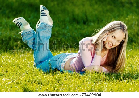 Delighted young woman on phone sitting on the grass