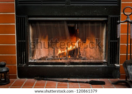 A fireplace surrounded by red brick, with a fire burning inside of it.