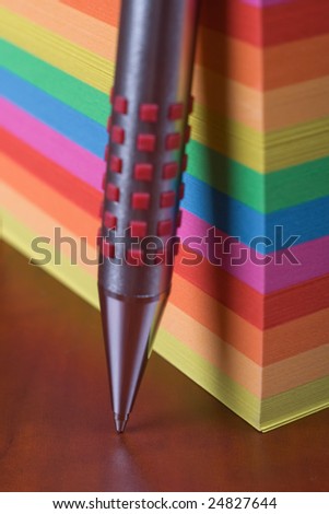 Stylish ballpoint pen near a block of colored notes