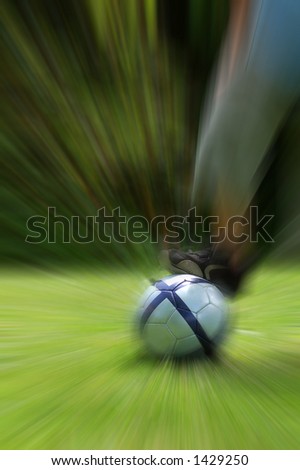 Kid playing football (soccer) - zooming effect (ball and foot sharp)