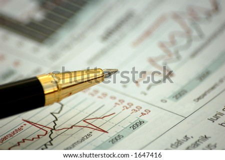 Golden pen showing curves on financial report/magazine