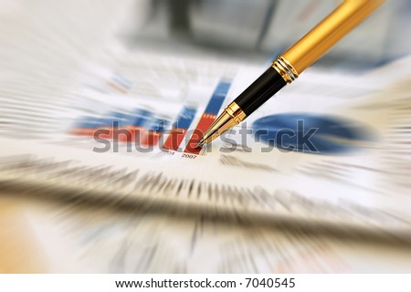 Golden Pen pointing on a diagram on an finance newspaper (zoom effect)