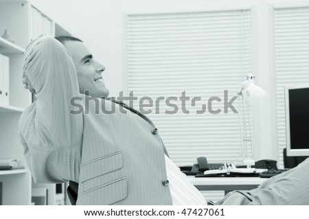 businessman relaxing in his office with a satisfied expression on his face