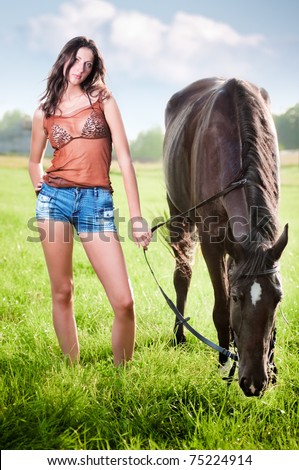 Young beautiful girl walking with a horse on the field