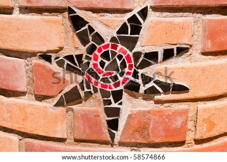 Star mosaic in black, red and white on brick.