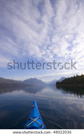 A touring kayak cuts through the water of Glacier National Park's Lake McDonald early in the morning