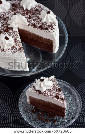 Cocoa and cream cake with slice on black background