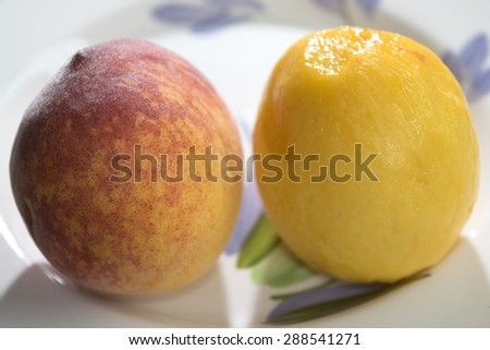 fresh peach of the field peeled and placed on a dish with a peach do not peeled