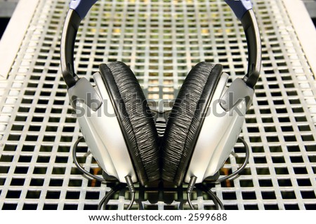 Symmetrical silver and black headphones on silver metal grid background