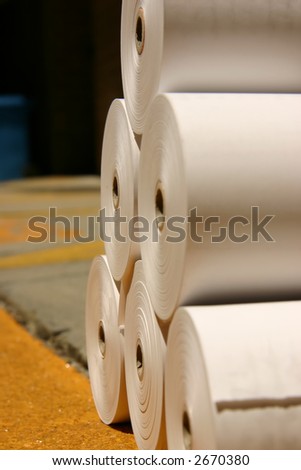 Rolls of white newspaper printing paper on a loading dock ready for delivery