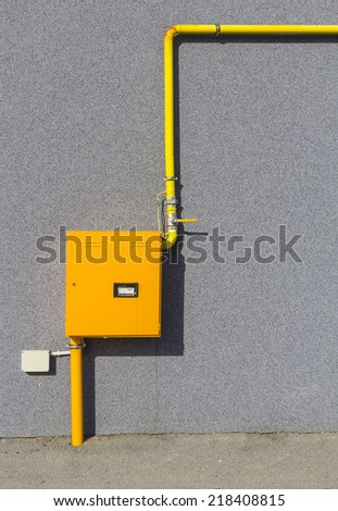 External Natural Gas Meter With Some Yellow Steel Pipes on Gray Wall