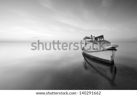 black and white photography of sky and sea at sunrise with a little old boat abandoned in the Mar Menor, Spain