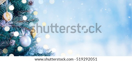 Decorated Christmas tree with bright bokeh on winter blue snowy background. Christmas banner.