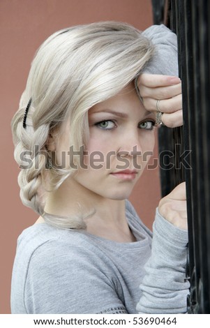 The woman with light hair and earrings in a grey dress keeps for the forged fence