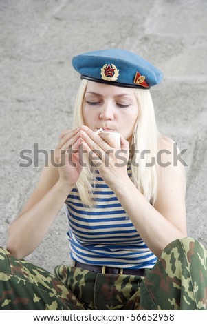 The woman in the military form sits and gets a light a cigarette