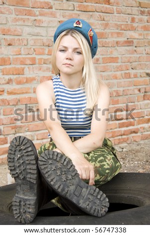 The woman in the military form sits on the tyre