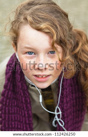 Outdoor portrait of a girl in winter cloths listening music player