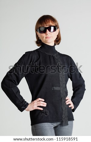 Studio portrait of a middle aged woman in sunglasses standing with arms akimbo
