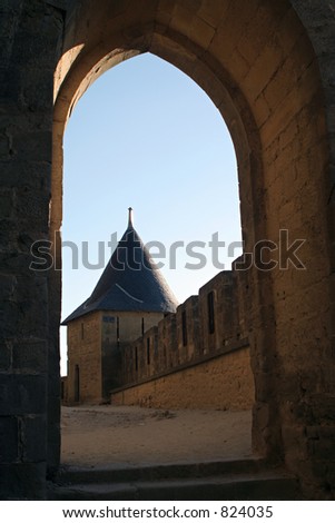 The castle of Carcassonne, France. View at a castle tower through an old stone archway in a sunny summer day. The sky is blue.