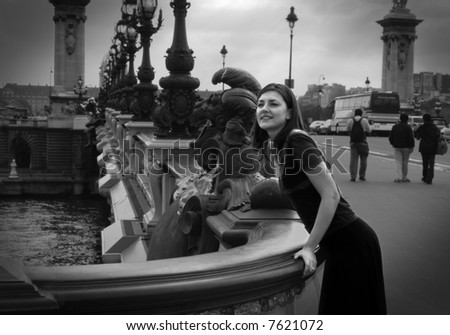 Black and white photo of a girl looking for somebody from a bridge; street scene in Paris