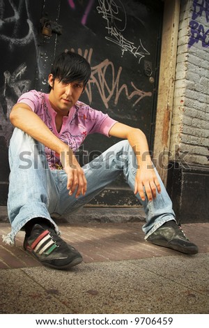 self-confident bad guy sitting on the ground in ghetto