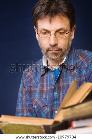 Mature man wearing glasses reads old book