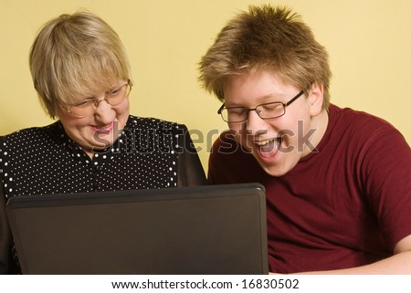 Teenager boy and his grandmother having fun with computer
