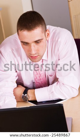 Serious young businessman looking at laptop screen