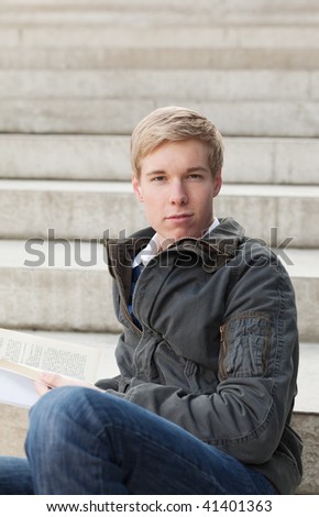 Young blond handsome guy sitting with a book
