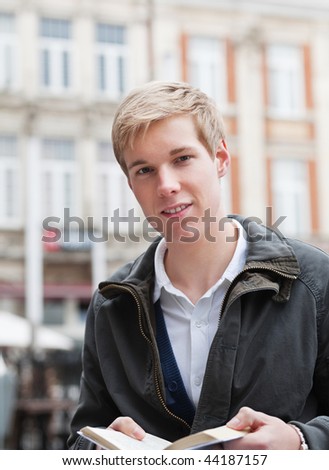 Young handsome man outdoors holding a book in his hands