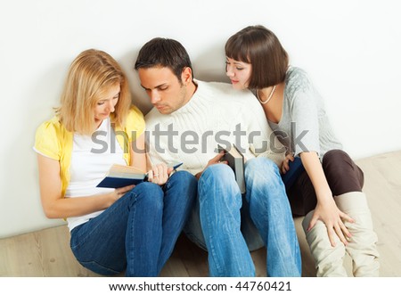 Three friends studying books together - one man and two young women