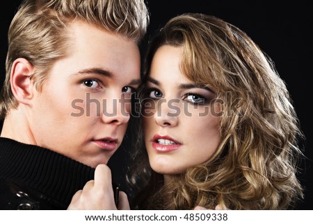 Closeup portrait of young handsome man and pretty woman in darkness