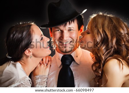 two pretty young women kissing smiling man from the sides