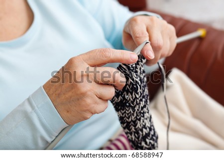 hands of an elder woman doing knitting at home