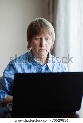 Elderly woman working with laptop computer at home