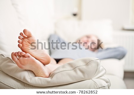 Barefoot young woman lying on sofa, shallow depth of field, focus on foot soles