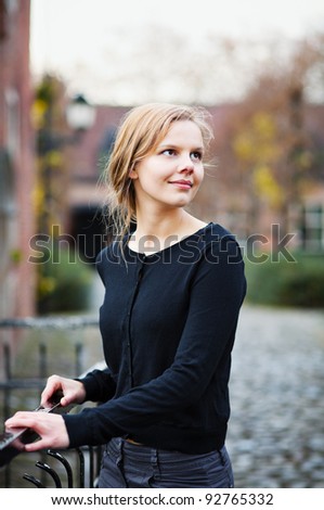 Portrait of a pretty young blond woman standing on a bridge in and turning back