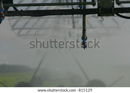 Detail of one spray head on a large center pivot irrigator with grass and spray mist in the background.  Canterbury, New Zealand.