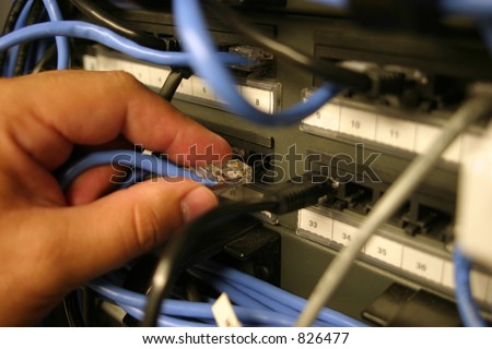 Plugging a black RJ45 into a patch panel.  Shallow DOF.  Focus is right on the end of the RJ45 being plugged in.