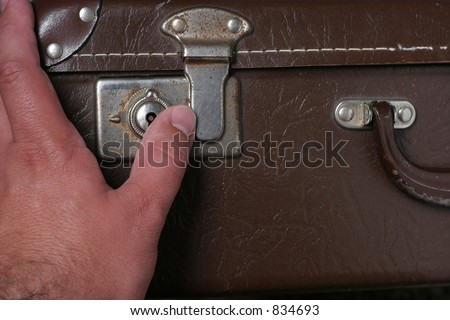 Opening the lock on an old leather look suitcase