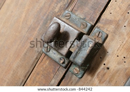 Latch on a 140 year old cupboard.  The timber is Rimu, native to New Zealand.  The latch and screws are a little rusty..