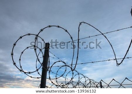 Corner post on a security fence with razor wire around the top.