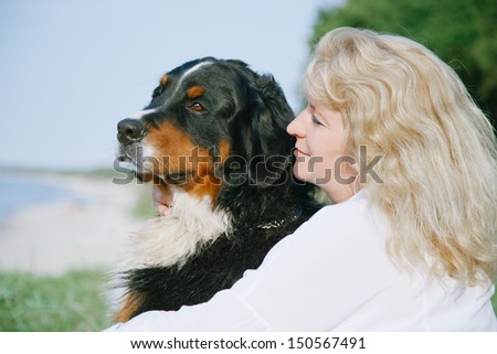 bernese mountain dog and woman looks aside at sea
