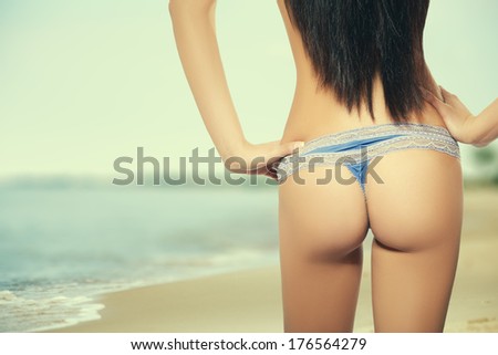 tanned buttocks in panties on sunny sea beach