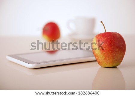 apples, tablet pc and coffee cup on table